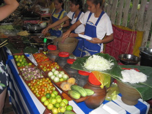 At the night market food stalls as she was making fresh green papaya salad from someone.  
